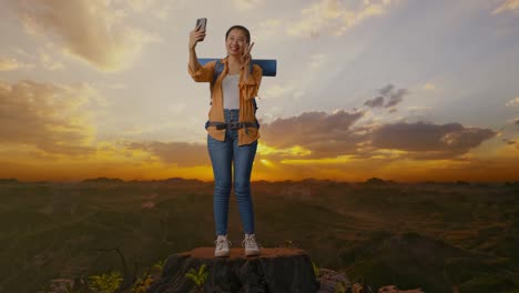 mujer feliz tomando una selfie en la cima de una montaña al atardecer