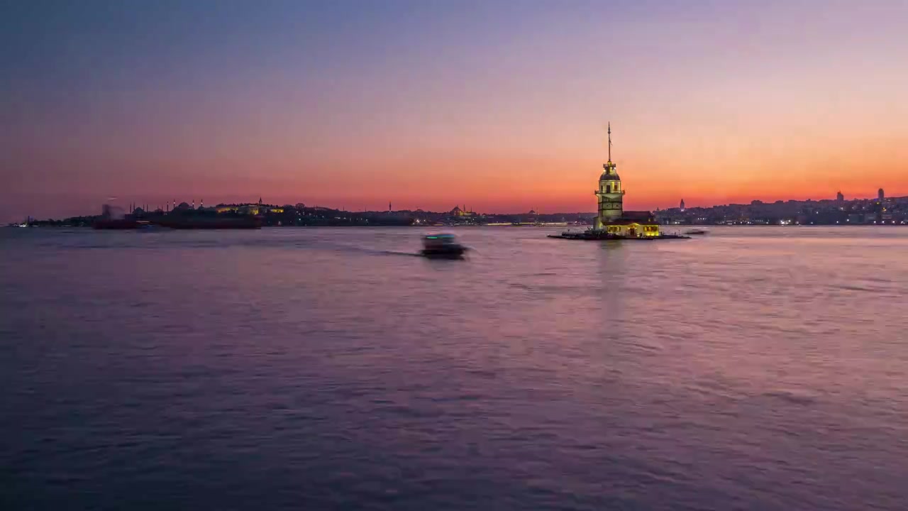 Mädchenturm nach Sonnenuntergang Tag-Nacht-Übergang Zeitraffer in Istanbul, Türkei, Kiz Kulesi Turm. Panoramische Stadtsilhouette im Hintergrund mit Reflexion auf dem Bosporus-Wasser.