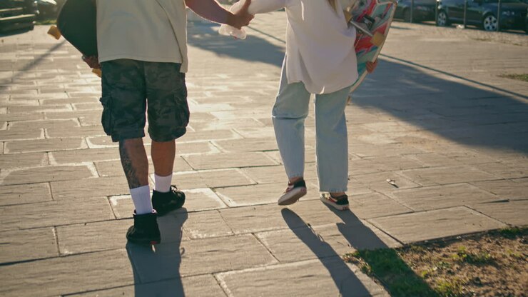 Couple legs walking sunbeams street back view. Lovers crossing avenue together