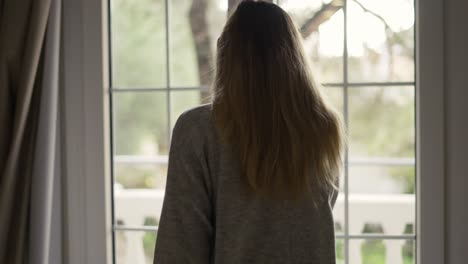 mujer abriendo cortinas en la habitación del hotel saliendo al balcón