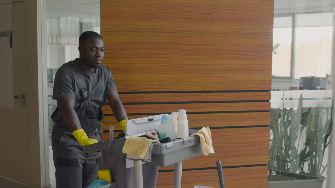 Cleaning Man Carrying A Cleaning Cart Inside An Office Building