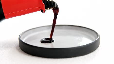 pouring soy sauce into plate on white background