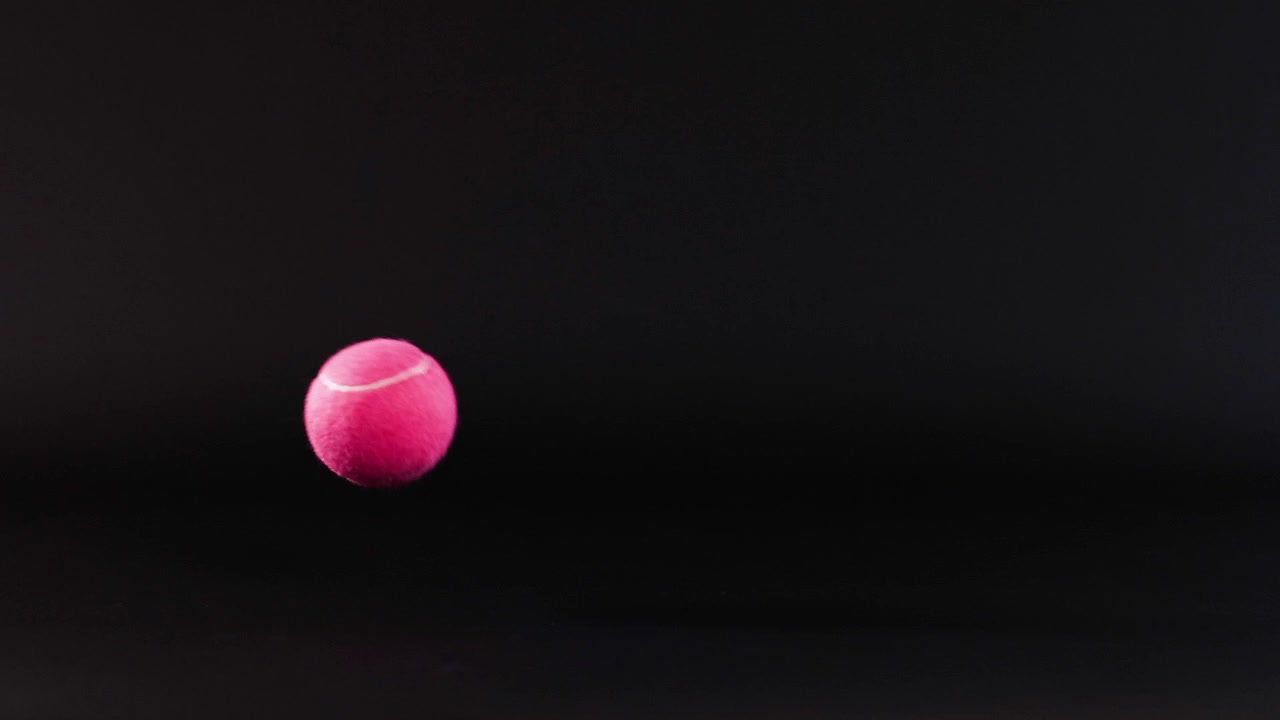 A tennis ball bounces on a dark surface