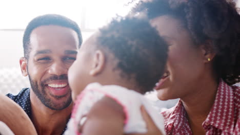 parents with baby daughter sitting on floor and playing with teddy bear at home