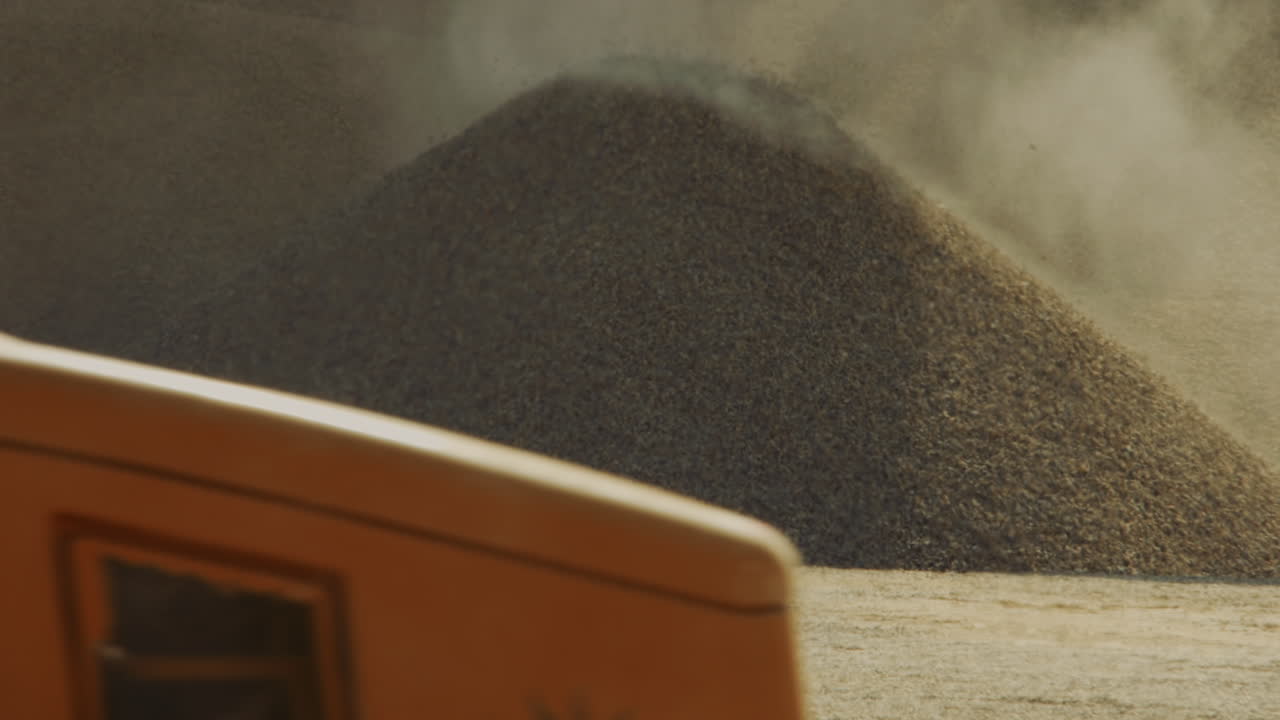 Large pile of grain with material being added
