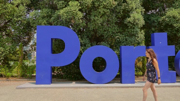Turista dai capelli rossi che cammina davanti a un cartello blu che indica la città di Porto con il famoso fiume Douro in Portogallo.