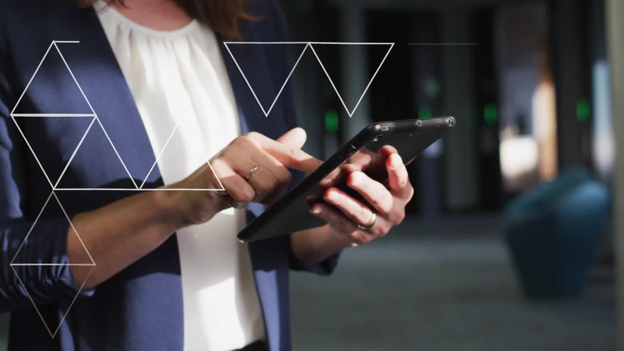 Businesswoman tapping tablet screen in corridor, activating wireframe triangles forming interface