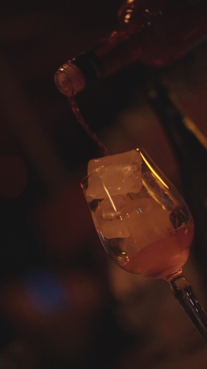 Versare la bevanda in un bicchiere pieno di cubetti di ghiaccio al bar.