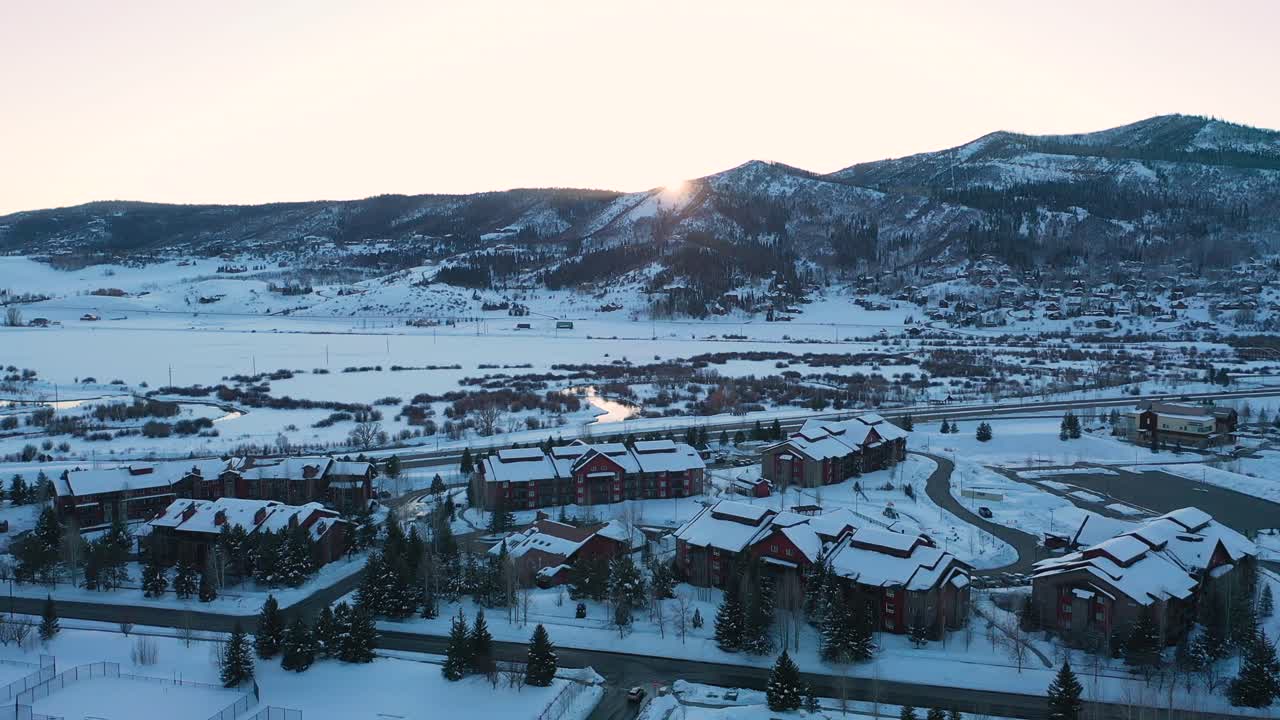 el sol se pone sobre los techos cubiertos de nieve y las cabañas en la estación de esquí steamboat en steamboat springs, colorado