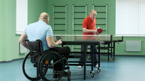 un hombre en silla de ruedas juega ping pong. personas con discapacidad juegan tenis de mesa. rehabilitación de discapacitados. deporte paralímpico.