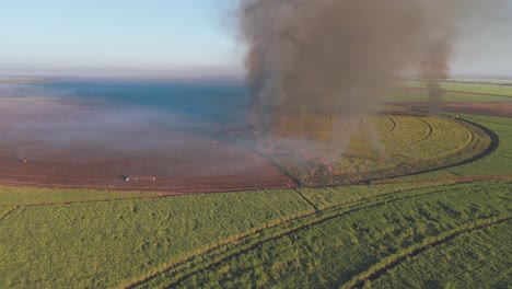 a slow aerial pan of a controlled fire that releases a lot of smoke