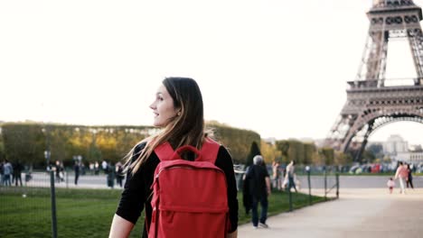 young happy woman with backpack walking alone near the eiffel tower and mars champs in paris, france