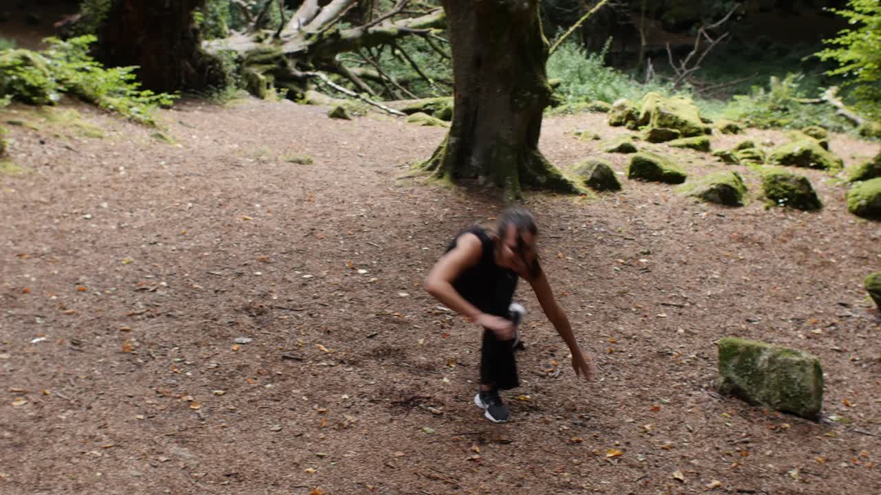 Joyful teenage girl trying out capoeira in forest meadow