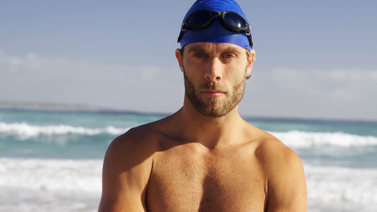 Ritratto di surfista uomo in piedi a braccia incrociate sulla spiaggia