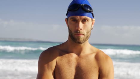 portrait of male surfer standing with arms crossed in the beach