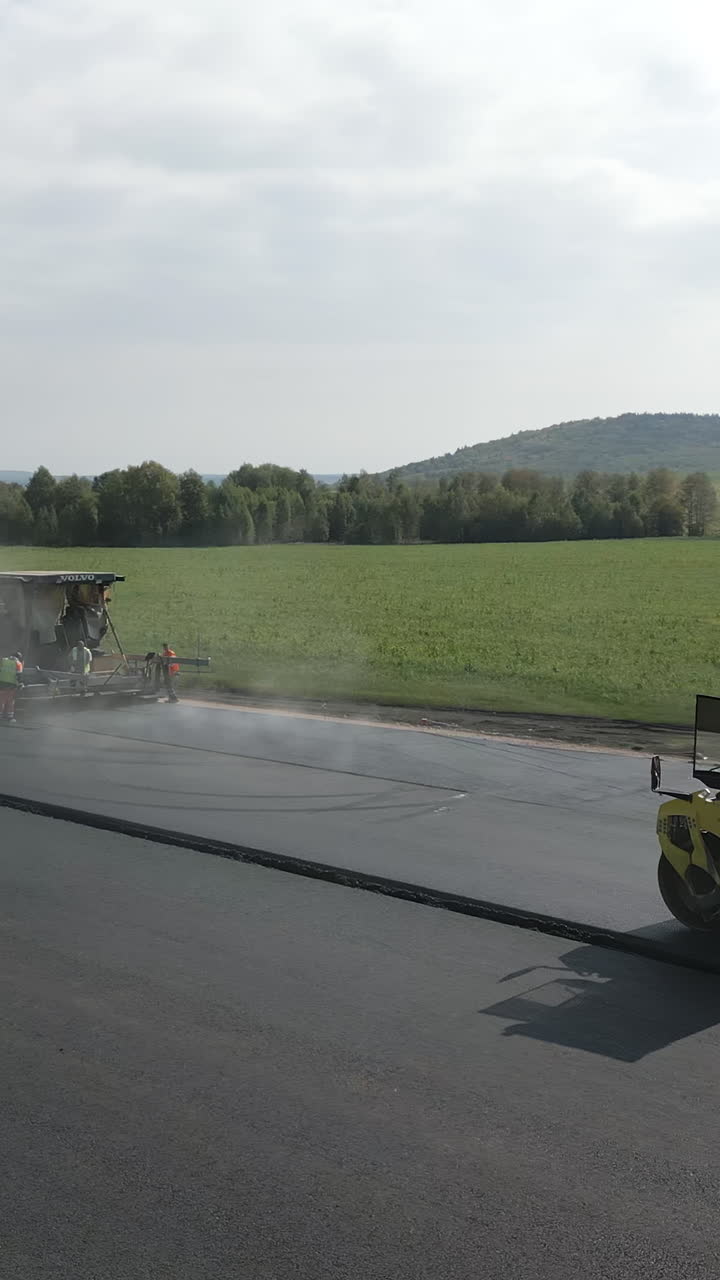 Road construction with asphalt paver and road roller