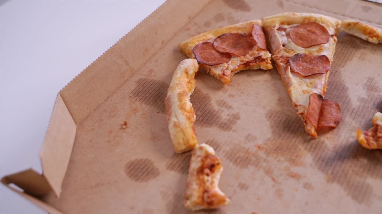 la cámara se desliza sobre una caja de pizza de pepperoni con pedazos comidos a mitad. entrega de comida rápida.