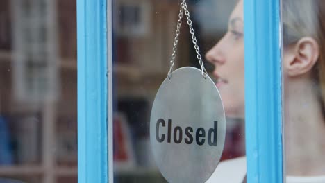 smiling small business owner turning around open sign on shop or store door