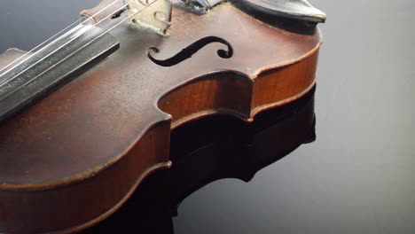 an expensive old vintage violin instrument resting on a shiny black grand piano in a symphony orchestra