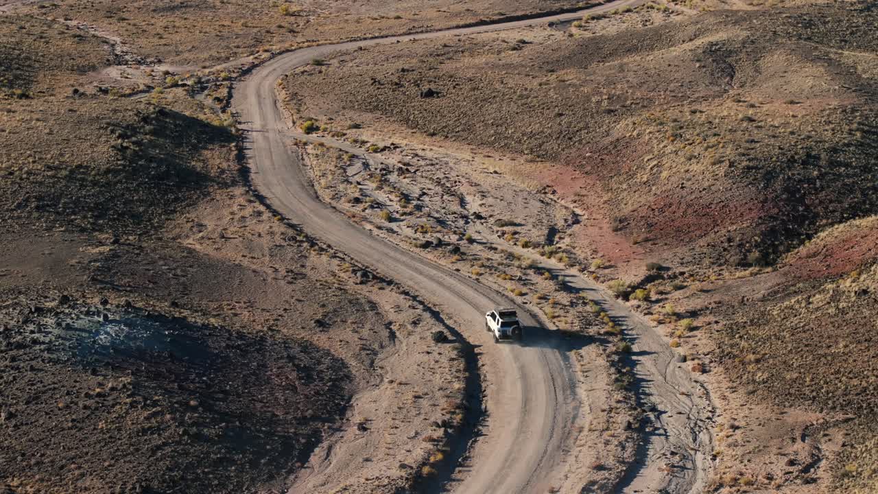 vehículo todoterreno conduciendo por una carretera sin pavimentar en el desierto de bentonite hills en utah, estados unidos