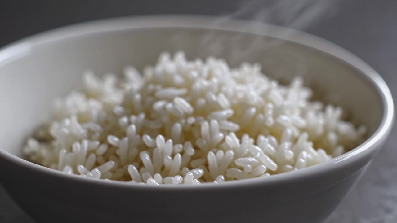 Close-up video of steaming white rice in a bowl, shot from a slightly elevated angle