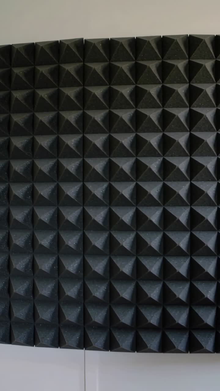 Vertical video: Panning camera revealing black pyramid foam panel in studio, highlighting seam