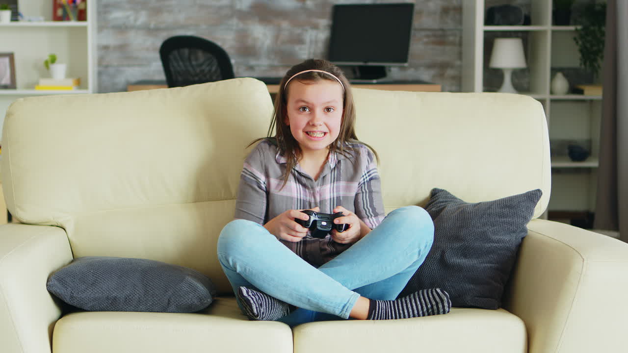 Cheerful little girl playing video games using wireless controller
