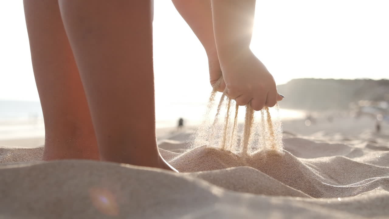 woman's hands taking sand from the beach at sunset, close-up. slow motion