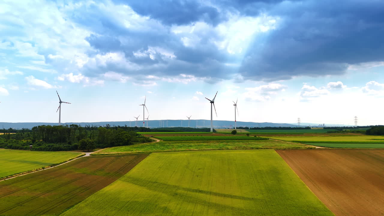Turbines produce energy in fields. Wind turbines stand tall in green fields under a clear sky, harnessing renewable energy in a sustainable landscape