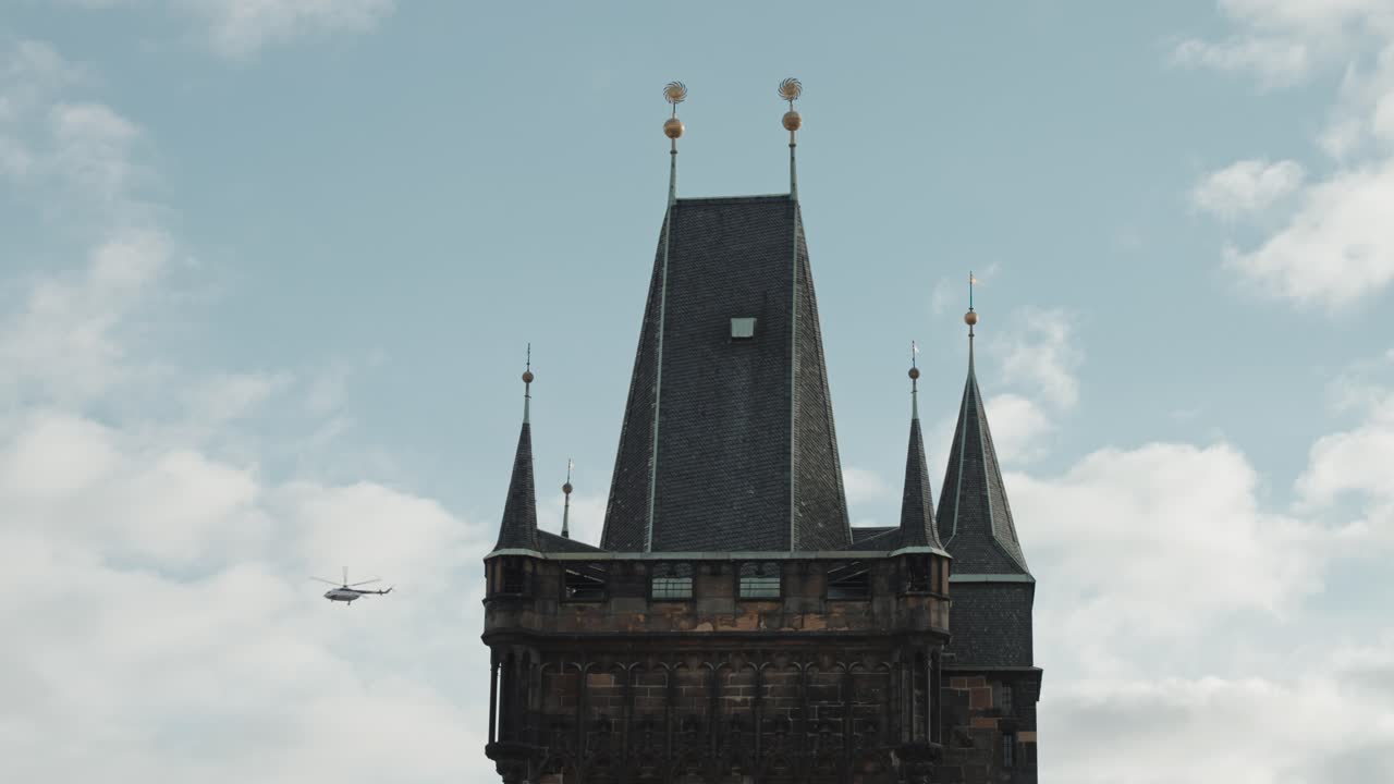 Helicopters fly by Old Town Bridge Tower, Prague under a cloudy sky