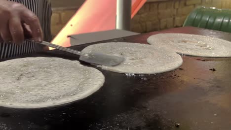 street food vendor making the famous masala dosa in bengaluru, india. close-up shot