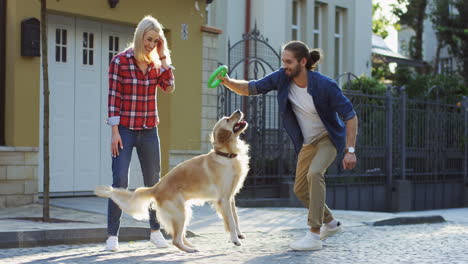joven y mujer jugando con un perro labrador en la calle en un día soleado
