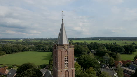 jib up of tall church tower in a small rural town overlooking green meadows