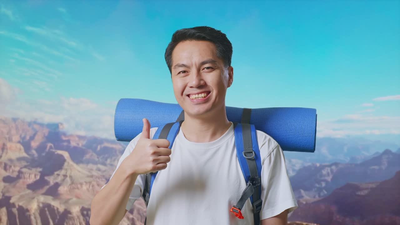 Close Up Of Asian Male Hiker With Mountaineering Backpack Smiling And Showing Thumbs Up Gesture To Camera While Traveling At The Top Of Mountain