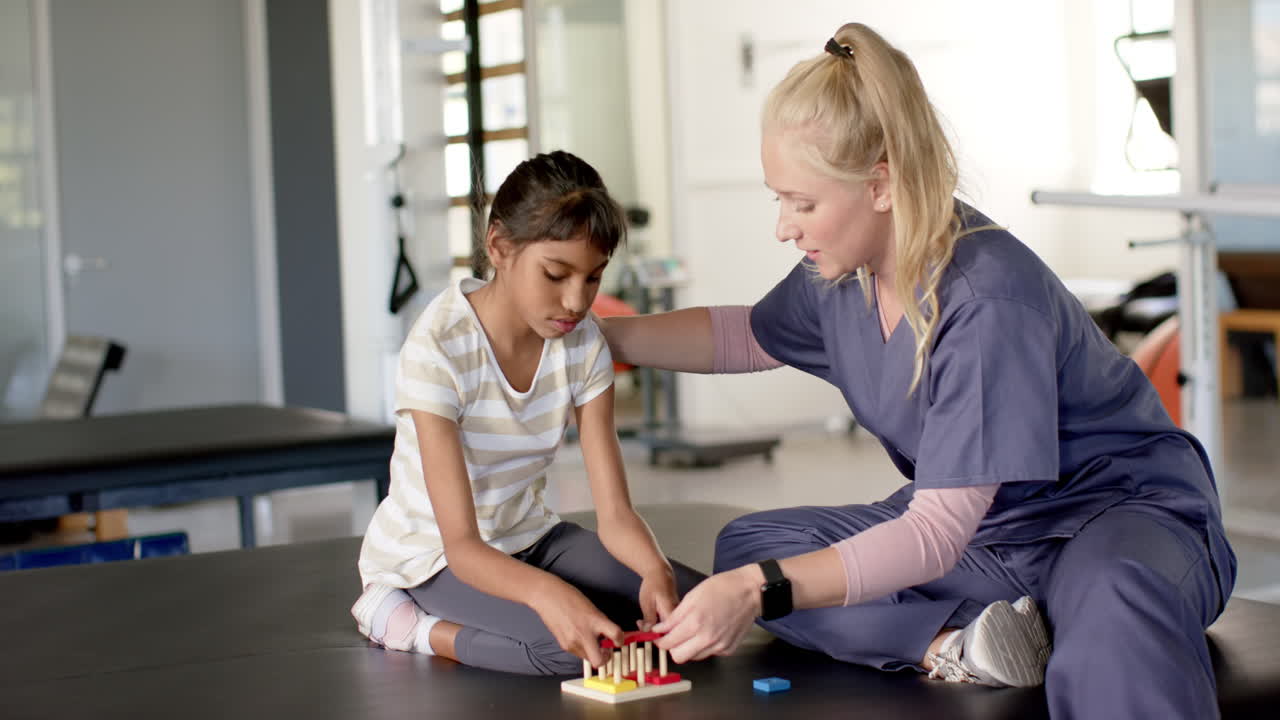 Assisting girl with cerebral palsy with disability, physical therapist during rehabilitation therapy