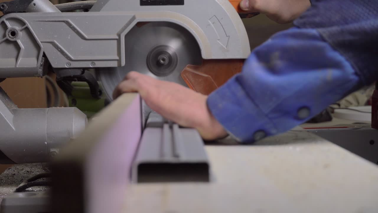 человек режет металлический профиль на режущей машине.