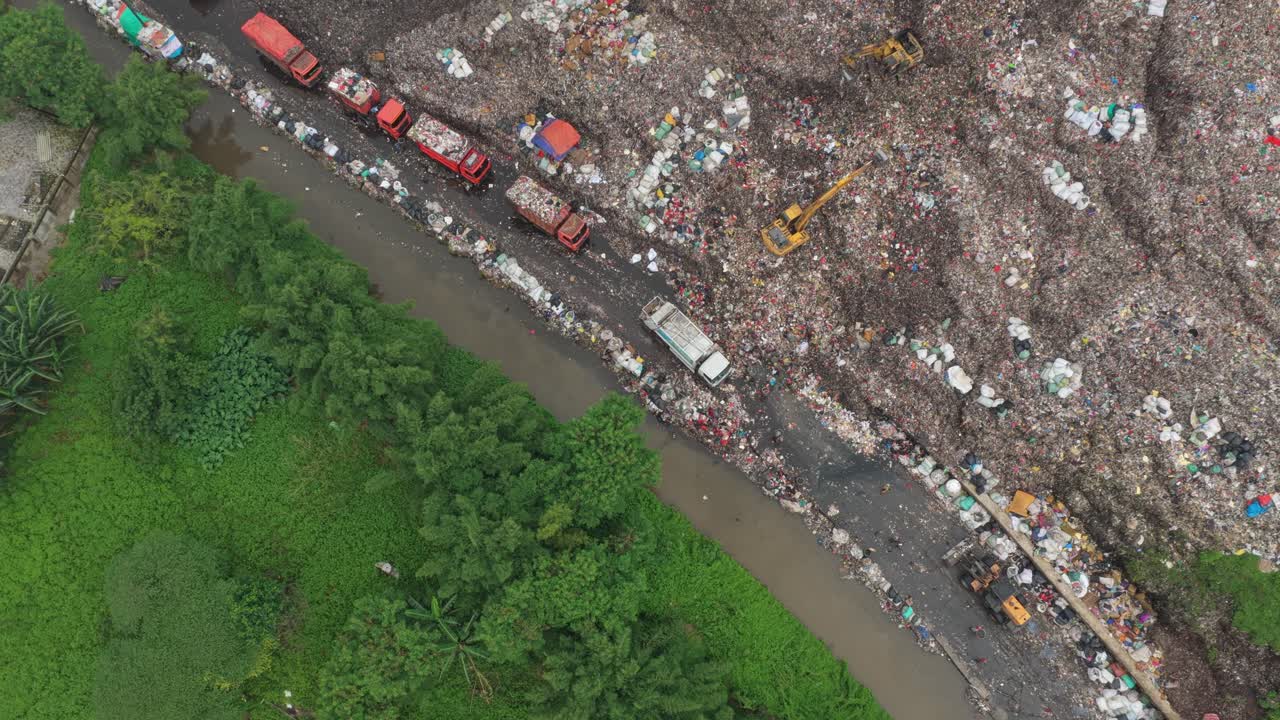 Aerial view of garbage trucks unloading waste at enormous landfill