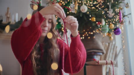 Beautiful-woman-using-red-ribbon-to-wrap-gifts-during-Christmas-at-home