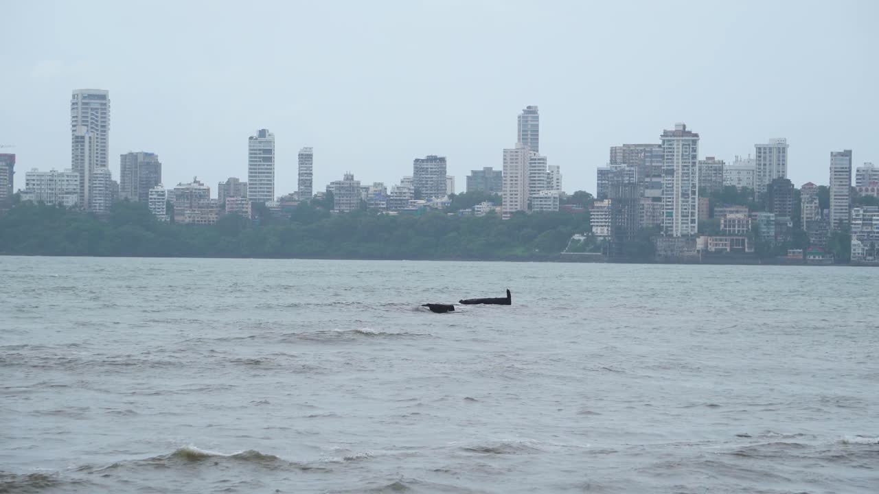 Edifici dello skyline di Mumbai con onde marine in una giornata monsonica nuvolosa.
