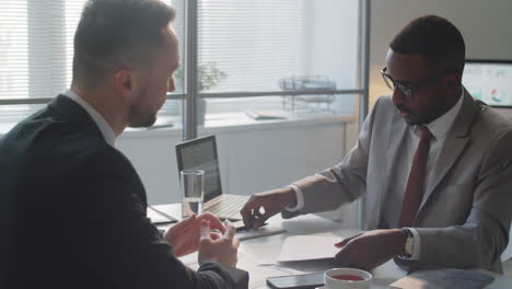 Two-Multiethnic-Businessmen-Signing-Contract-and-Shaking-Hands-in-Office