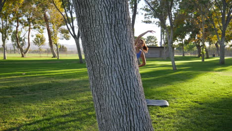 A-pretty-young-hispanic-woman-stretching-and-loosening-up-her-body-before-a-workout-in-the-park-at-sunset-SLOW-MOTION