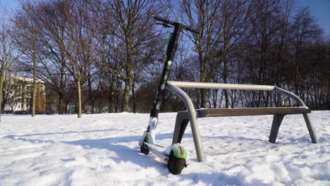 電動滑板車被遺棄在公園中,在雪淋<unk>的冬天滑板