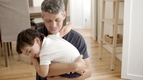 Happy-dad-holding-little-son-in-arms-and-cuddling-him