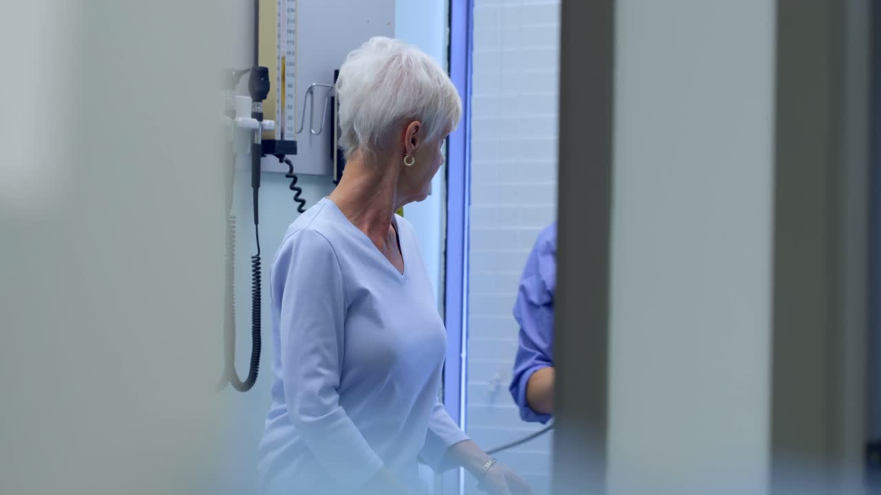 médico controlando la presión arterial de un paciente de edad avanzada medidor de presión arterial en la clínica 4k