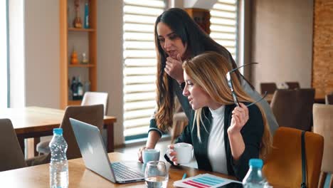 dos mujeres de negocios jóvenes revisan las noticias del mercado de criptomonedas en una computadora portátil, se regocijan porque el precio se disparó