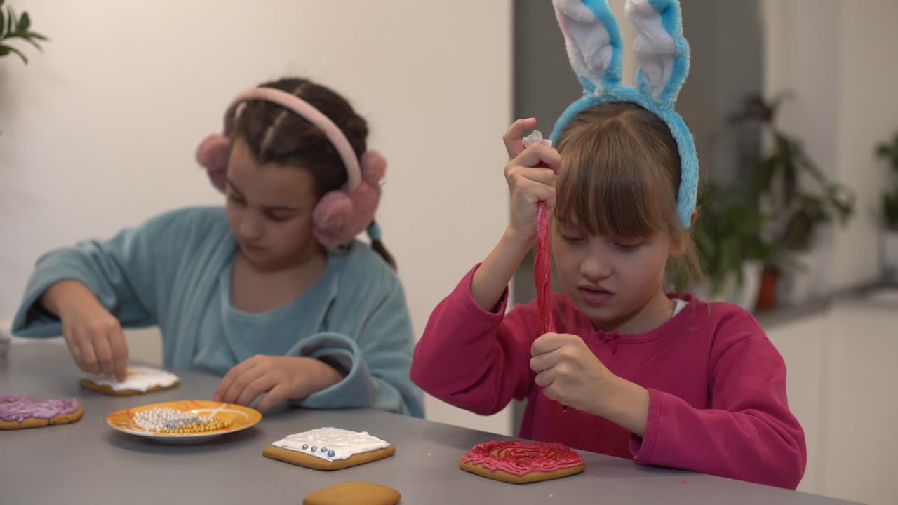 dos hermanas pequeñas decorando galletas caseras en la cocina en casa.