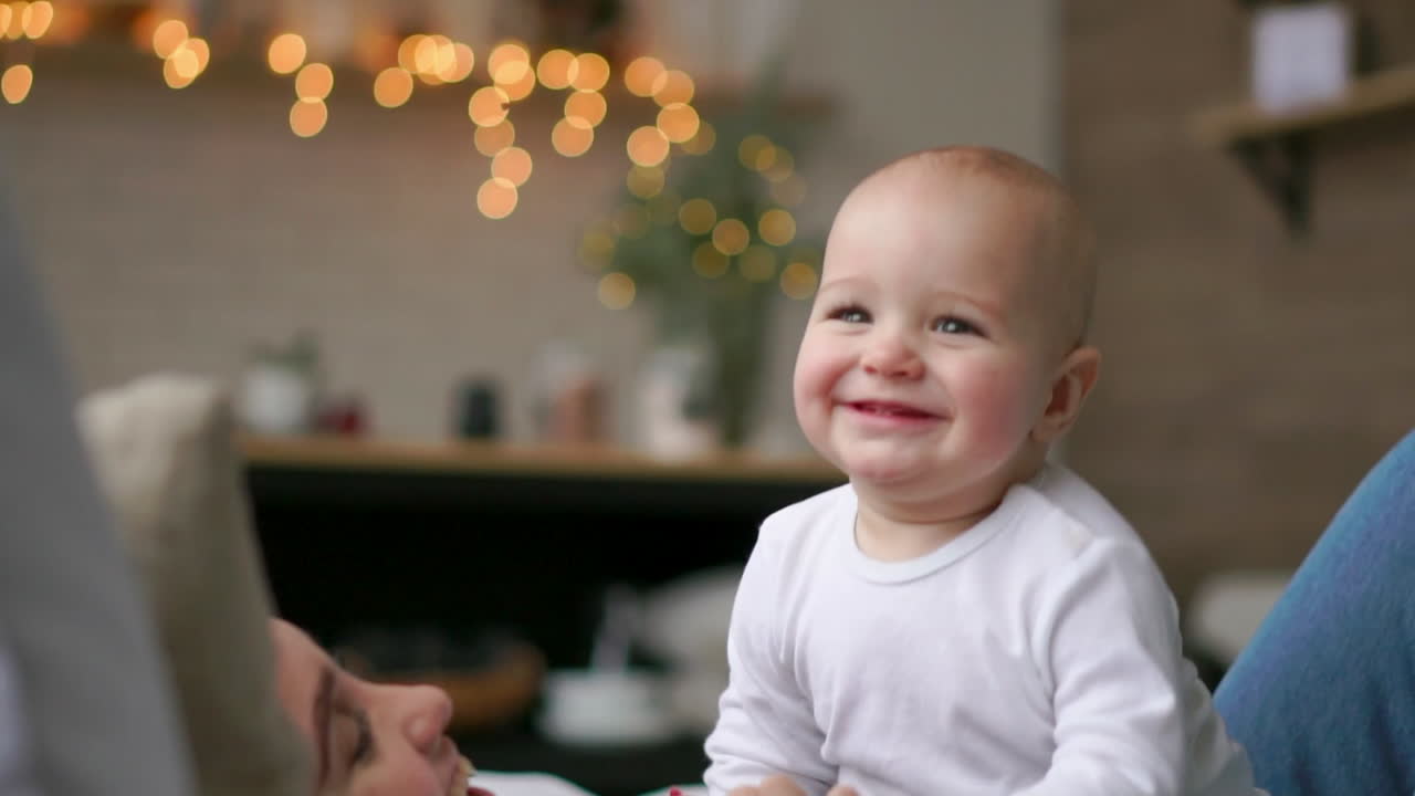 귀여운 어린 소녀가 침대 위에서 아들과 함께 놀고 있습니다. 젊은 어머니는 침대 위에서 아기와 함께 놀고 있습니다.