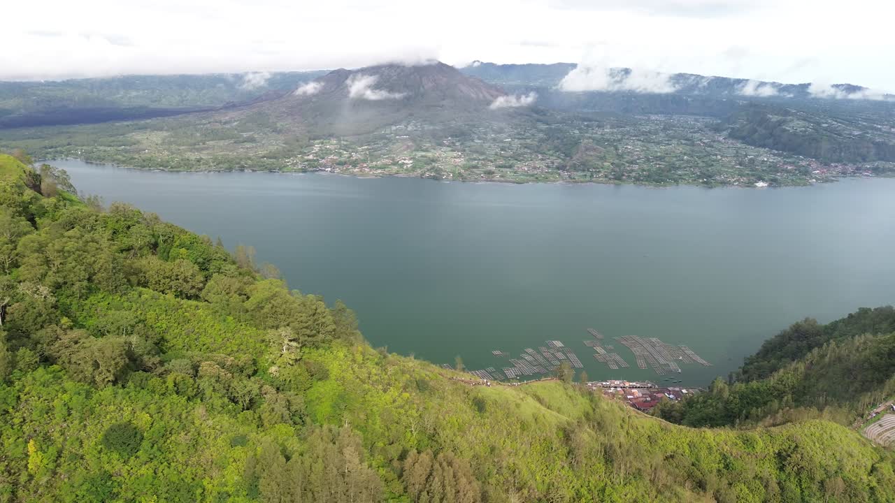 exuberantes colinas verdes y un lago tranquilo con montañas brumosas en la distancia, vista aérea
