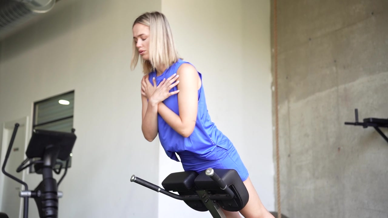 Una donna si allena su una panca per iperestensioni, mostrando attività atletiche e di fitness in palestra.