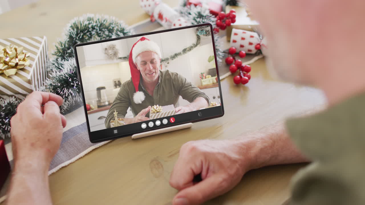 hombre caucásico con decoraciones de navidad teniendo llamada de video de tableta con hombre caucàsico feliz